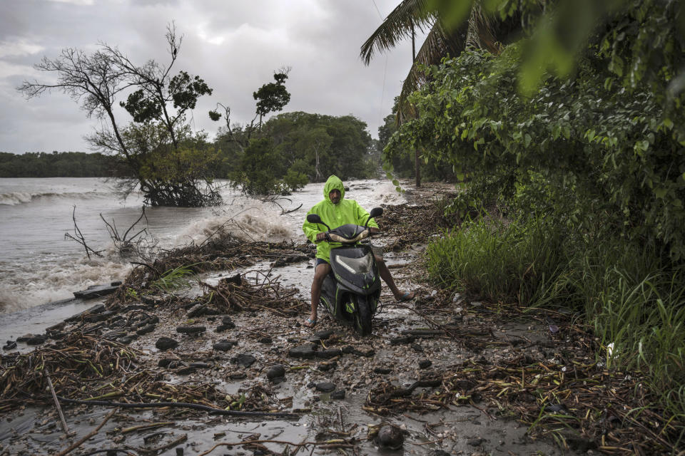 Delmer Torres rides his motorcycle on a road covered by debris left from flooding driven by a Gulf of Mexico sea-level rise in his coastal community of El Bosque, in the state of Tabasco, Mexico, Tuesday, Nov. 28, 2023. (AP Photo/Felix Marquez)
