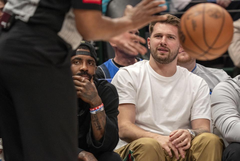 Dallas Mavericks' Luka Doncic, right, and Kyrie Irving, left, watch from the bench during the second half of an NBA basketball game against the Detroit Pistons, Friday, April 12, 2024, in Dallas. Doncic and Irving were not playing due to injuries. (AP Photo/Jeffrey McWhorter)