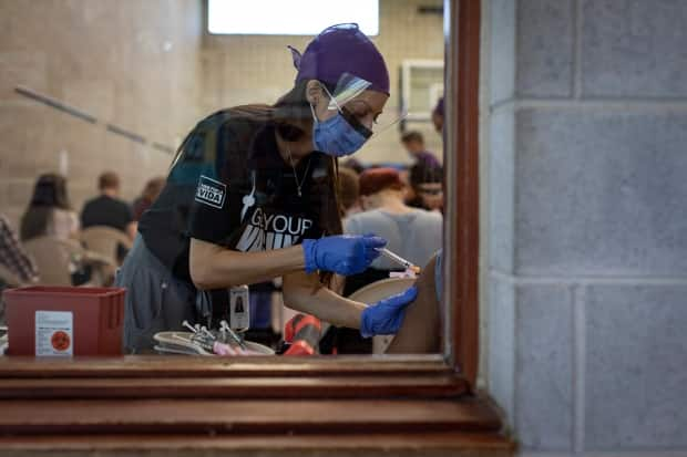 Health-care workers with Humber River Hospital administer doses of the Moderna COVID-19 vaccine at a temporary clinic for members of Toronto’s Spanish-speaking community at the Glen Long Community Centre on May 14, 2021. (Evan Mitsui/CBC - image credit)