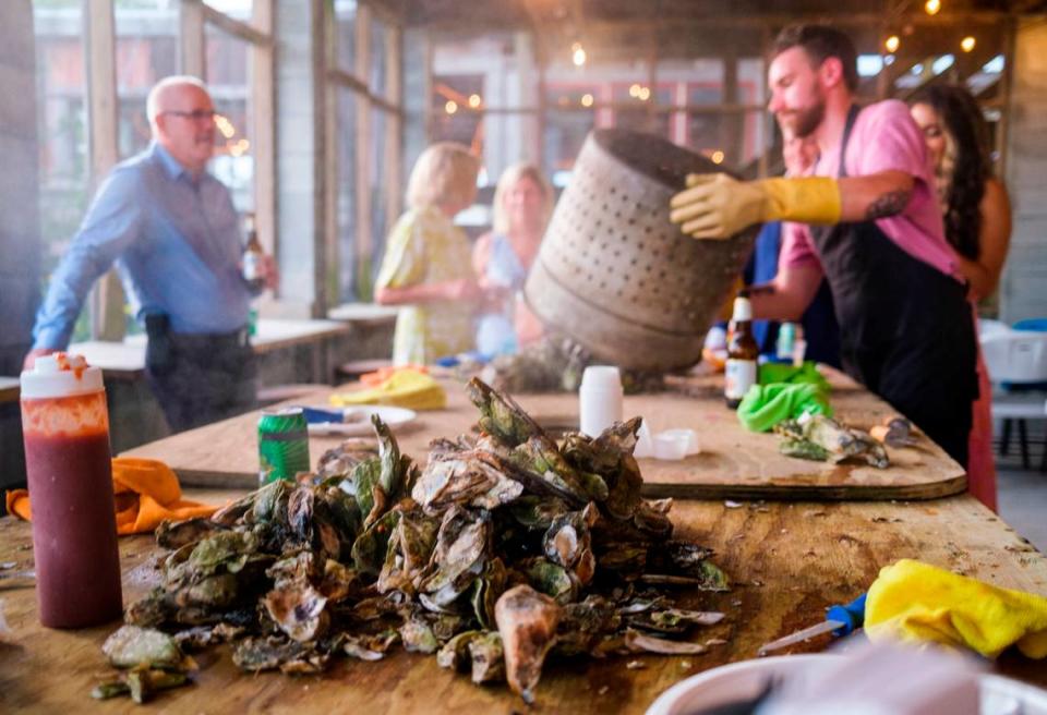 Tyler Howerton pours steaming oysters onto a table at Bowen’s Island Restaurant during an oyster roast event for a wedding rehearsal party with some of the season’s first oysters from the Folly River near Charleston, S.C. Oct. 8, 2021.