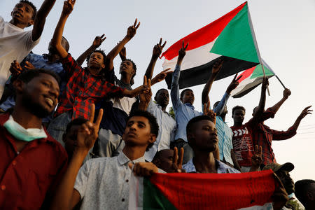 Sudanese demonstrators make victory signs and wave Sudanese flags as they protest in front of the Defence Ministry in Khartoum, Sudan April 17, 2019. REUTERS/Umit Bektas