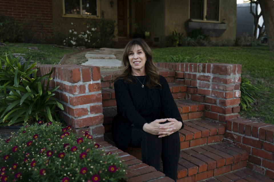 Jacki Graham, a 64-year-old COVID survivor, sits for a photo outside her home in Los Angeles, Thursday, Jan. 20, 2022. In the fall of 2020, she became so fatigued that her morning yoga would send her back to bed. “I’m an early riser, so I’d get up and push myself, but then I was done for the day. ... Six months ago, I would have told you COVID has ruined my life.” (AP Photo/Jae C. Hong)