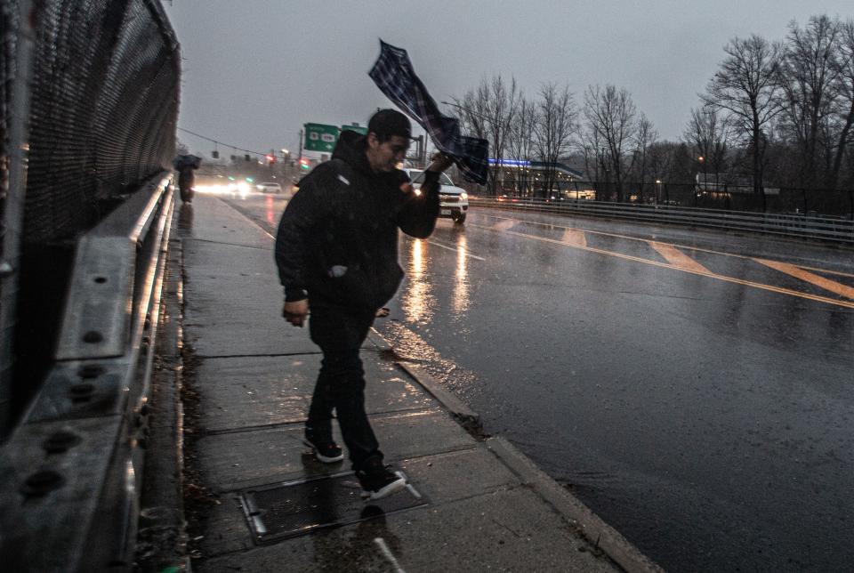 A pedestrian walks through heavy rain and wind on route 9 in Tarrytown, N.Y. Monday morning, Dec. 18, 2023. The intense storm battered much of the East Coast, causing flash flooding and power outages.