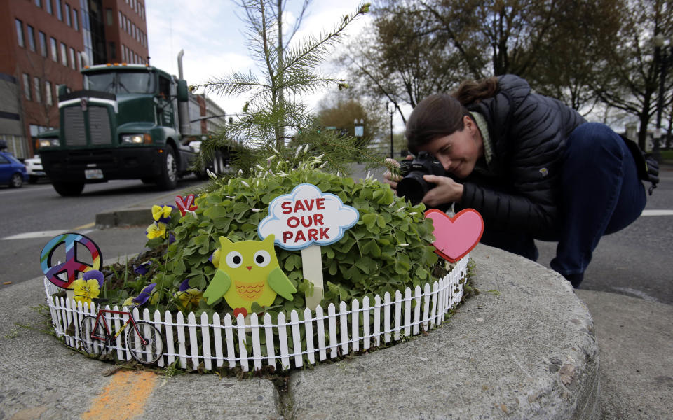 Allison Wildman crouches low to get a photo of Mill Ends Park in Portland, Ore., Thursday, April 11, 2013. Tiny battle lines are being drawn in a whimsical British-American dispute over which country has the world’s smallest park. Two feet in diameter, Portland’s Mill Ends Park holds the title of world’s smallest park in the Guinness Book of World Records. But a rival has emerged--Prince’s Park, more than 5,000 miles away in the English town of Burntwood which holds the record for smallest park in the United Kingdom.(AP Photo/Don Ryan)