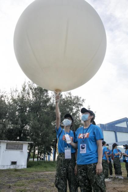 學員參訪空軍馬公基地天氣中心，教官解說探空氣球功用，在施放前也讓學生體驗抓在手掌中的感覺，看起來像是動畫片「天外奇蹟」的場景，學子把握難得機會合影。（軍聞社吳東昇）