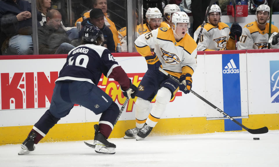 Nashville Predators center Juuso Parssinen, right, looks to pass the puck as Colorado Avalanche defenseman Samuel Girard covers him in the second period of an NHL hockey game Saturday, Dec. 17, 2022, in Denver. (AP Photo/David Zalubowski)