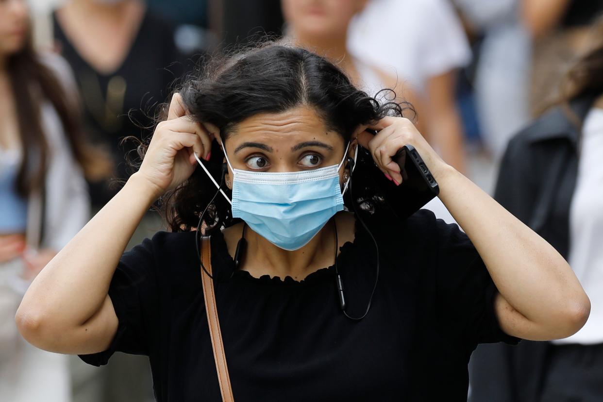 A shopper adjusts her face mask on Oxford Street om London on July 24, 2020, after wearing facemasks in shops and supermarkets became compulsory in England as a measure to combat the spread of the novel coronavirus. (Photo by Tolga AKMEN / AFP) (Photo by TOLGA AKMEN/AFP via Getty Images)