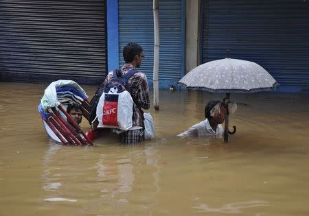 People use a cycle rickshaw to commute through a flooded road after heavy rains in the northeastern Indian city of Guwahati September 23, 2014. REUTERS/Utpal Baruah