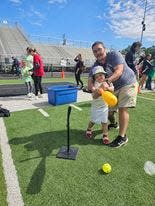 Liam Wigington, 4, is all smiles, as his dad, David, helps him take a swing. It was the first time the Jackson Local preschooler participated in the Exceptional Olympics.