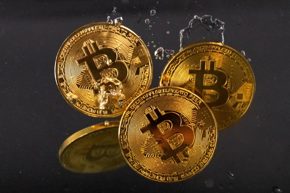 Suvenýrové tokeny představující kryptoměnu Bitcoin se na tomto obrázku pořízeném 17. května 2022 ponoří do vody. REUTERS/Dado Ruvic/Ilustrace