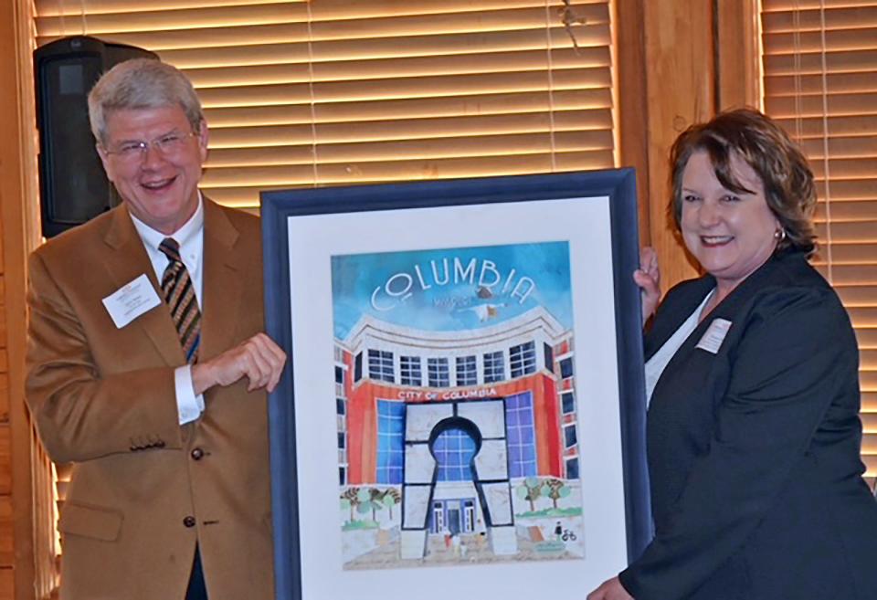 John Baker accepts a retirement gift Wednesday from Community Foundation of Central Missouri Board Chair Susan Hart, as he steps down from his role as executive director.