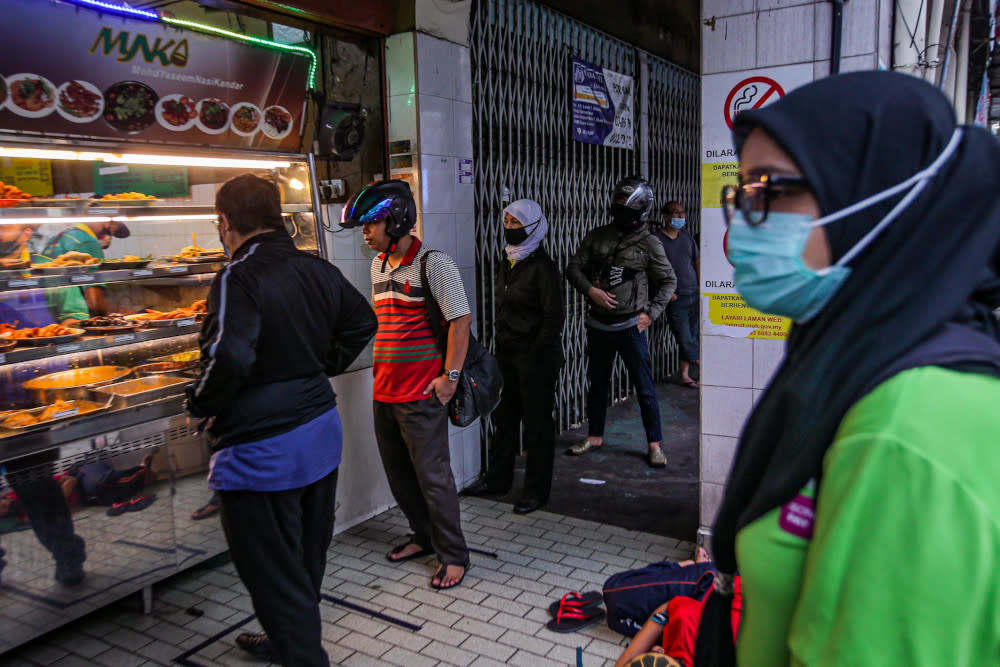 Customers queue up to buy food at an eatery in Kuala Lumpur. — Picture by Hari Anggara