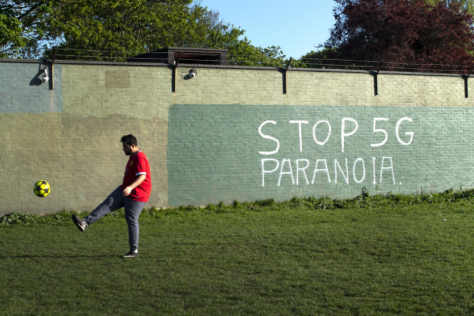 A man plays football in front of graffiti reading Stop 5G Paranoia on Wanstead Flats in East London as the UK continues in lockdown to help curb the spread of the coronavirus.