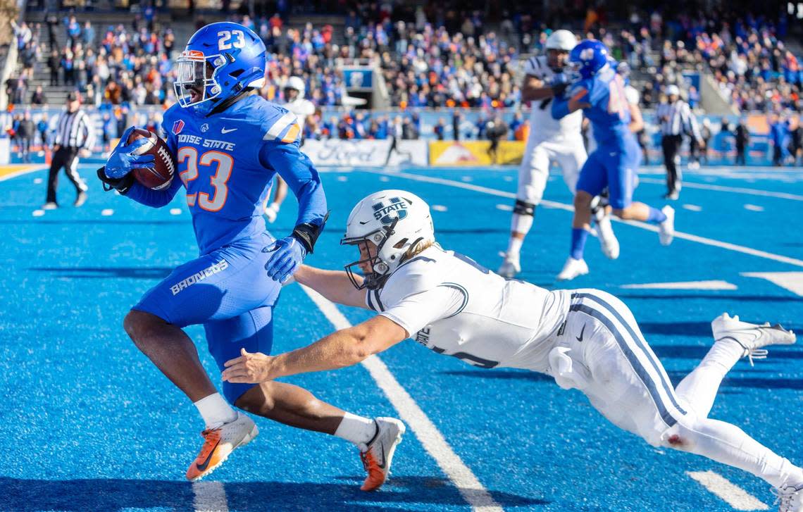 Boise State safety Seyi Oladipo heads into the end zone on a 48-yard interception touchdown run with Utah State quarterback Cooper Legas trailing behind him in the fourth quarter of their football game against Utah State at Albertsons Stadium on Friday, Nov. 25, 2022.