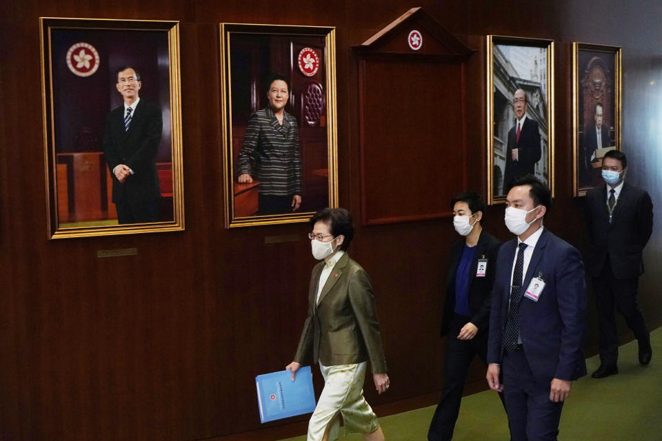 Hong Kong Chief Executive Carrie Lam, left, arrives the chamber for her policy address in the Legislative Council in Hong Kong, Wednesday, Nov. 25, 2020. Lam said Wednesday that the city's new national security law has been “remarkably effective in restoring stability” after months of political unrest, and that bringing normalcy back to the political system is an urgent priority. (AP Photo/Kin Cheung)