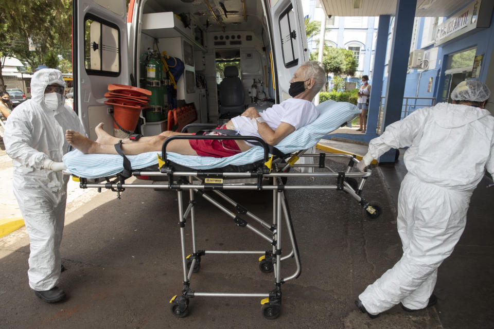 Health workers pull a COVID-19 patient from an ambulance into Santa Casa Hospital in Jau, Brazil, Thursday, Jan. 28, 2021. The Santa Casa hospital is operating at full capacity and patients take turns receiving oxygen. (AP Photo/Andre Penner)