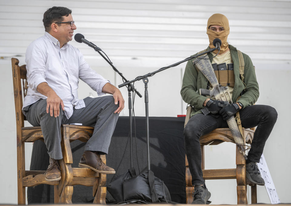 Host Pablo Martinez, left, interviews a man named Mike who holds his assault rifle during a Second Amendment Protest in response to Gov. Michelle Lujan Grisham's recent public health order suspending the conceal and open carry of guns in and around Albuquerque for 30-days, Tuesday, Sept. 12, 2023, in Albuquerque, N.M. (AP Photo/Roberto E. Rosales)