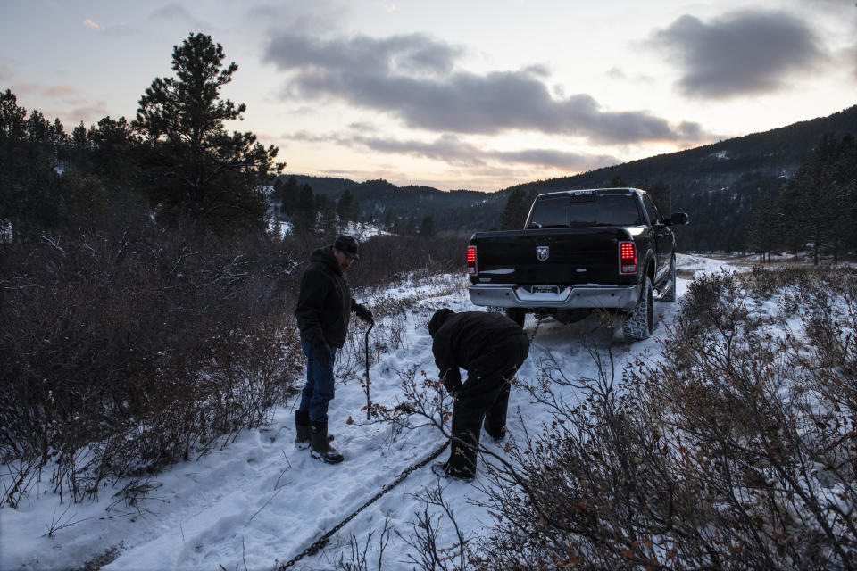 Richard King, 70, and his brother, Brent, right, work to pull Richard's truck out of the mud on the family ranch near Zortman, Mont., on the Fort Belknap Indian Reservation on Sunday, Dec. 8, 2019. Richard was sexually abused on the Assiniboine reservation in Fort Belknap, Montana, where he grew up. He said taboos and shame kept him silent decades. Instead he abused alcohol and drugs. That, he believes, is how tribal members dealt with the abuses they face, rather than speaking out. (AP Photo/Tommy Martino)