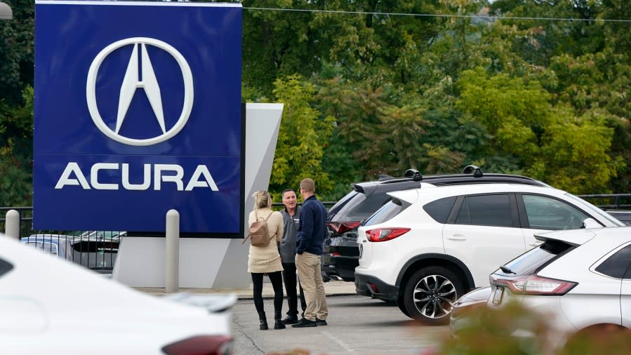 FILE – A salesman talks with customers in an Acura dealership lot in Wexford, Pa., on Sept. 29, 2022. (AP Photo/Gene J. Puskar, File)