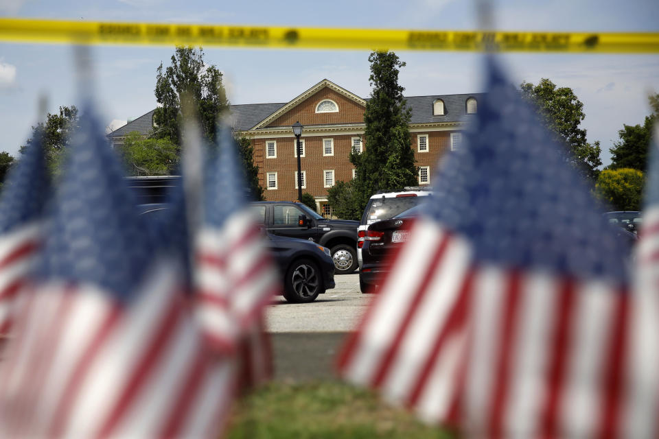 American flags that are part of a makeshift memorial stand at the edge of a police cordon in front of a municipal building that was the scene of a shooting, Saturday, June 1, 2019, in Virginia Beach, Va. DeWayne Craddock, a longtime city employee, opened fire at the building Friday before police shot and killed him, authorities said. (AP Photo/Patrick Semansky)