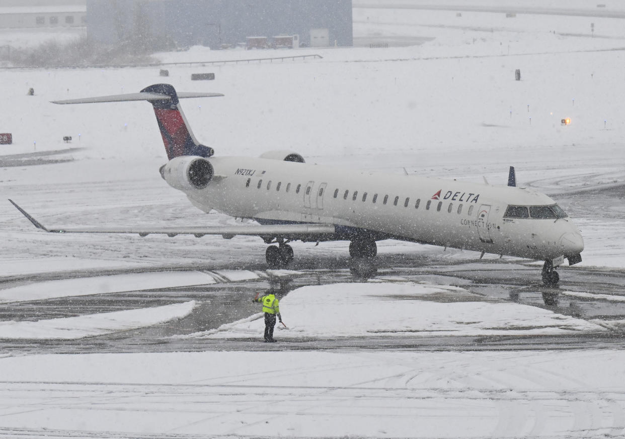 A Delta airline flight lands as crews remove snow from the Albany International Airport during a winter snow storm Tuesday, March 14, 2023, in Albany, N.Y. (AP Photo/Hans Pennink)