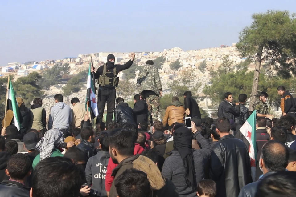 FILE - In this frame grab from video taken on Dec. 20, 2019, militants of the al-Qaida-linked Hayat Tahrir al-Sham try to disperse people who have gathered at the Bab al-Hawa border gate to protest the ongoing bombing campaign in Syria's rebel-controlled Idlib province by the government and its Russian ally. Intermingled among 3 million civilians under siege in the Syrian government's assault on the last opposition stronghold are tens of thousands of al-Qaida-linked fighters and other militants who came from around the world to take part in the country's civil war. (AP Photo, File)