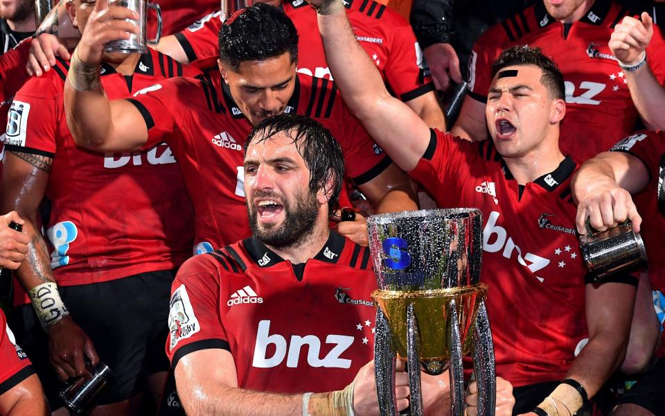 Sam Whitlock of the Canterbury Crusaders holds the trophy as he celebrates with team mates after they defeated South Africa's Lions