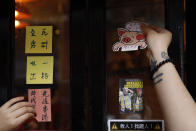 An employee removes stickers and posters with messages in support of the pro-democracy movement at a restaurant in Hong Kong, Thursday, July 2, 2020. Hong Kong police have made the first arrests under a new national security law imposed by mainland China, as thousands of people defied tear gas and pepper pellets to protest against it. Police say they arrested 10 people under the law, including at least one who was carrying a Hong Kong independence flag. (AP Photo/Kin Cheung)