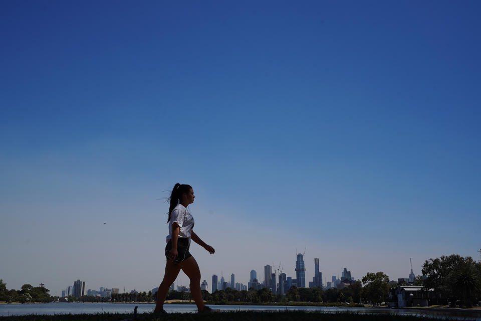 A walker braves the heat to walk around Albert Park lake during hot weather in Melbourne.