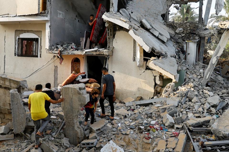 Palestinians carry out belongings from a damaged house, following Israeli strikes, in Khan Younis (REUTERS)