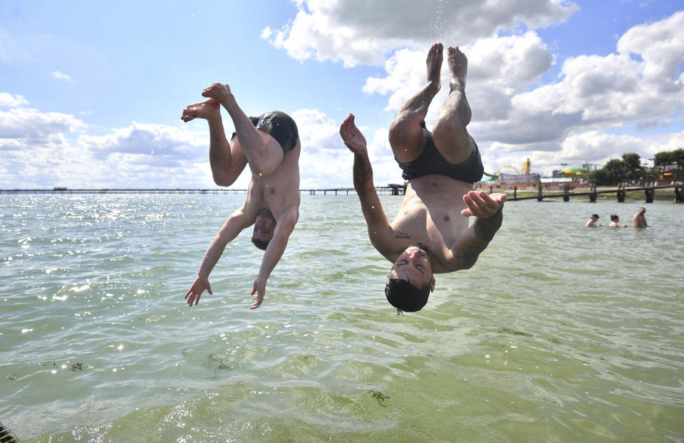 Men jump from a jetty into the water as the hot weather continues, at Southend-on-Sea, in England, Sunday, Aug. 2, 2020. (Victoria Jones/PA via AP)