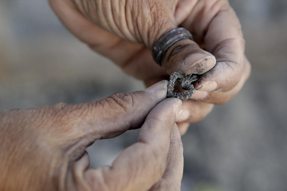 Bernadette Laos looks at jewelry she salvaged from her home that was destroyed by the Kincade Fire near Geyserville, Calif., Thursday, Oct. 31, 2019. (AP Photo/Charlie Riedel)