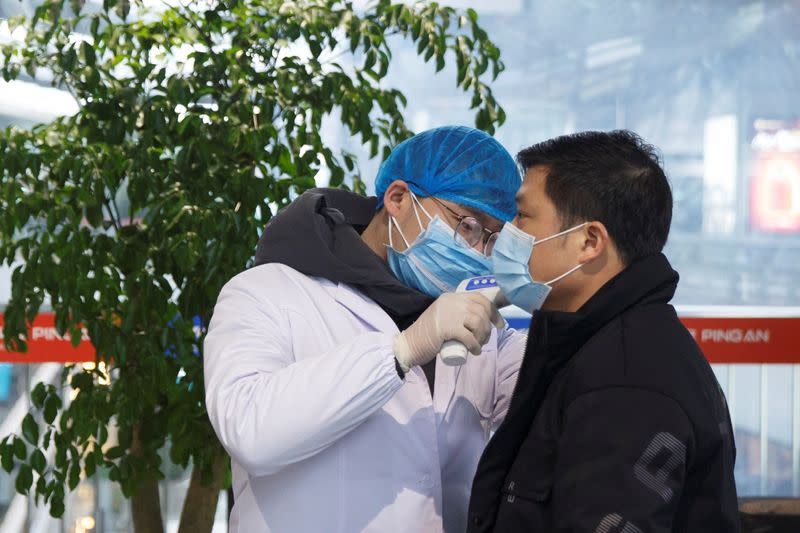 Un trabajador de salud toma la temperatura corporal a un hombre en la sala de embarques del aeropuerto de Changsha, en la provincia de Hunan, como medida de precaución debido al brote de coronavirus. Enero 27, 2020. REUTERS/Thomas Peter