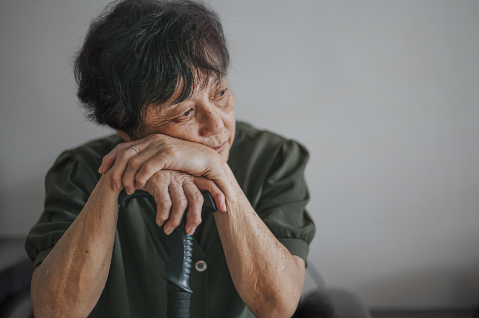 Elderly person resting chin on hands, leaning on a cane, thoughtful expression, in a discussion about retirement planning