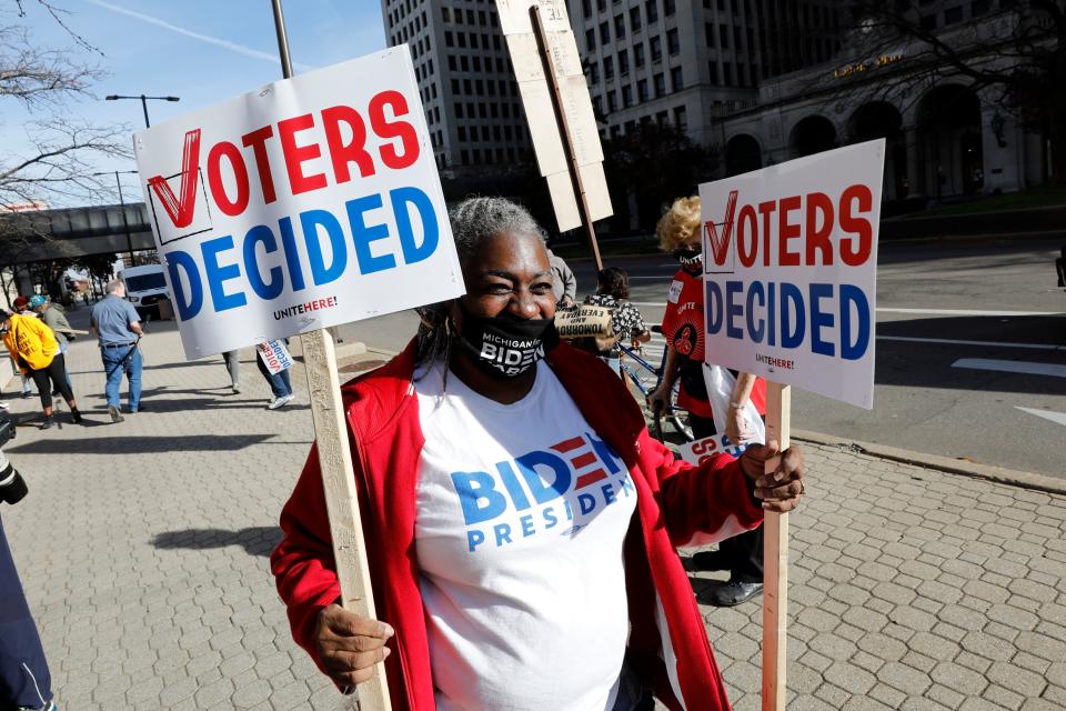 Zinnia Patcas hands out signs as people gather to celebrate Joe Biden's win in the presidential election on November 7, 2020 in Detroit, Michigan. (Jeff Kowalsky/AFP via Getty Images)