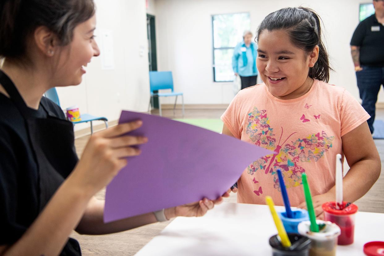 Jimena Ortiz, left, an intern with the Asheville Area Chamber of Commerce, shows Nathalie Palma, 8, her painted handprint June 27, 2023 at the Verner Center for Early Learning.