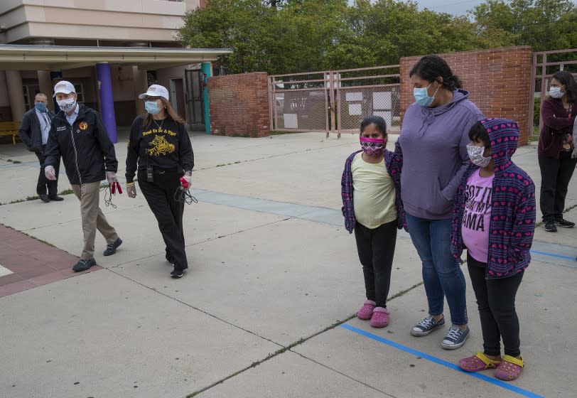 SAN FERNANDO, CA-APRIL 20, 2020: LAUSD Superintendent Austin Beutner, left, walks with principal Flora Mendoza-Werner during a tour of one of the district's Grab & Go food centers at San Fernando Senior High School, where meals were given out to LAUSD students in need. They are wearing protective masks against the spread of the coronavirus. (Mel Melcon/Los Angeles Times)