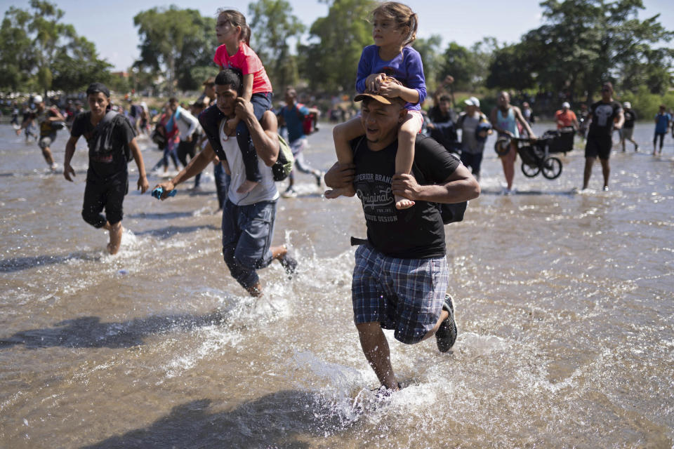 Central American migrants carry children as they run across the Suchiate River from Guatemala to Mexico, near Ciudad Hidalgo, Mexico, Monday, Jan. 20, 2020. More than a thousand Central American migrants hoping to reach United States marooned in Guatemala are walking en masse across a river leading to Mexico in an attempt to convince authorities there to allow them passage through the country. (AP Photo/Santiago Billy)