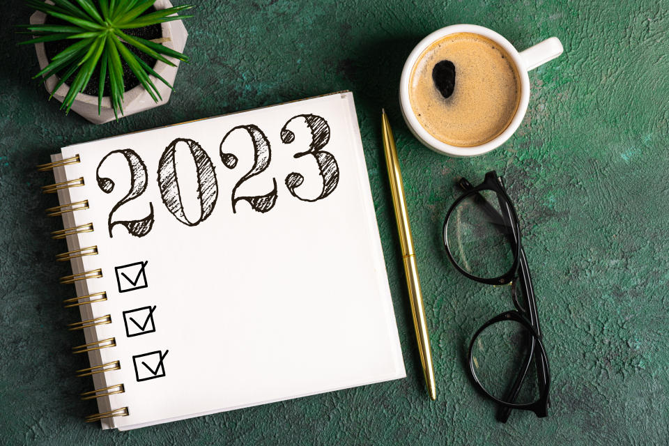 money New year resolutions 2023 on desk. 2023 resolutions list with notebook, coffee cup on table. Goals, resolutions, plan, action, checklist concept. New Year 2023 background. Copy space