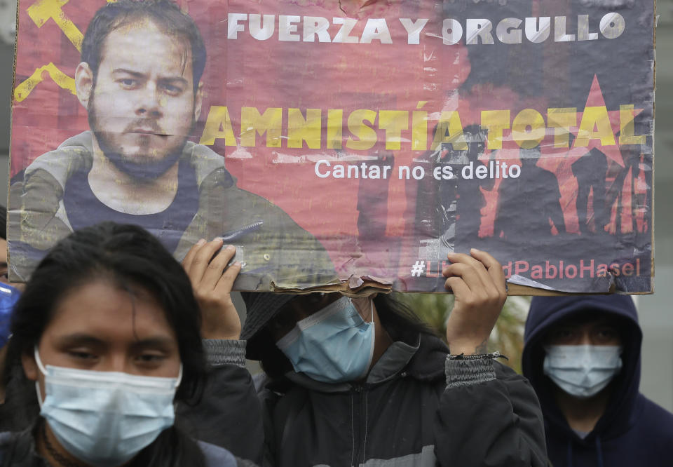 Demonstrators protest Spain's arrest of rap singer Pablo Hasel, convicted of insulting the Spanish monarchy and praising terrorist violence, outside Spain's consulate in Quito, Ecuador, Friday, Feb. 19, 2021. The sign reads in Spanish "Strength and Pride. Total amnesty. Singing is not a crime." (AP Photo/Dolores Ochoa)
