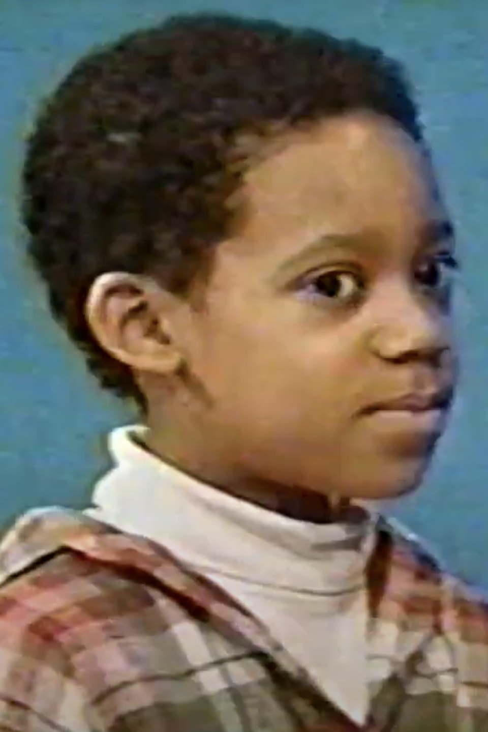 Young Tyler James Williams with a serious expression, wearing a plaid shirt over a turtleneck