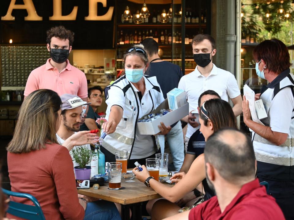 Anti-Covid mediators deliver hand sanitiser to customers on a bar terrace in Strasbourg (AFP via Getty Images)