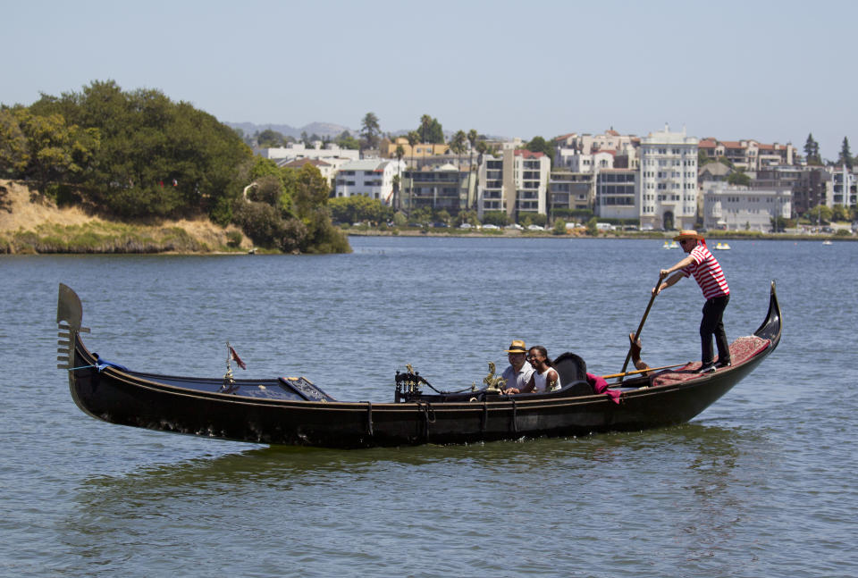 In this photo taken Wednesday July 4, 2012 a couple rides a gondola on Lake Merritt in Oakland, Calif. It’s not easy being Oakland. Growing up in the shadow of an icon is never a shoe-in, whether you’re a wannabe princess related to that attention-grabbing vamp Cinderella or a city living next door to fabled San Francisco. (AP Photo/Eric Risberg)