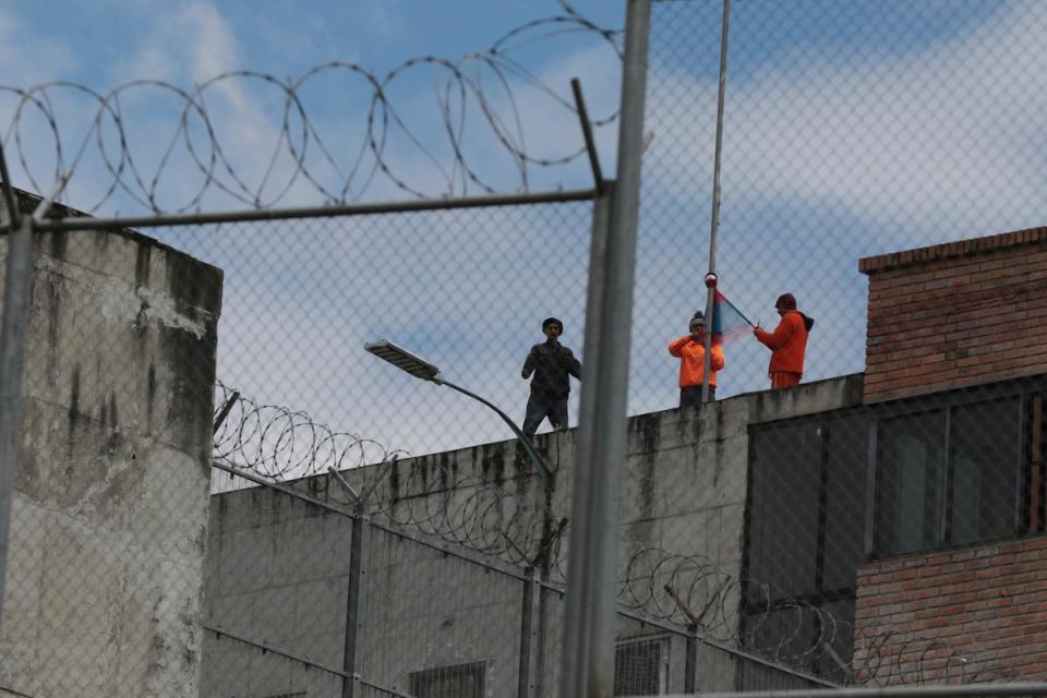 Inmates stand on the top of Turi jail during a prisoner riot in Cuenca (AP)