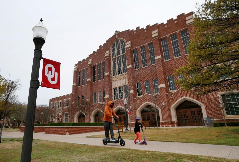 Two people ride scooters past McCasland Field House on the University of Oklahoma campus in Norman, Okla., Tuesday, March 17, 2020. [Nate Billings/The Oklahoman]