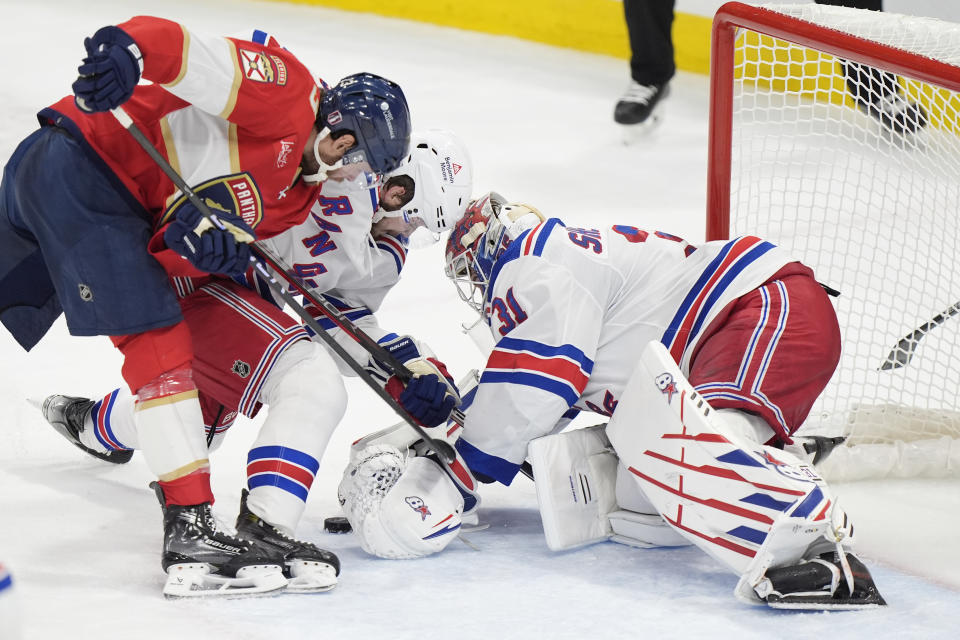 Florida Panthers center Carter Verhaeghe, left, attempts a shot at New York Rangers defenseman Ryan Lindgren, center, and goaltender Igor Shesterkin, right, during the second period of Game 4 during the Eastern Conference finals of the NHL hockey Stanley Cup playoffs, Tuesday, May 28, 2024, in Sunrise, Fla. (AP Photo/Wilfredo Lee)