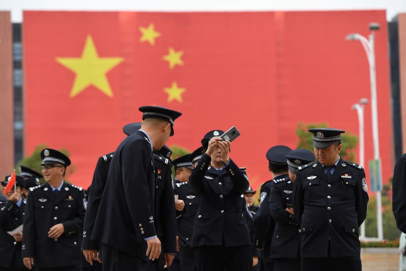 Police officer takes pictures with a mobile phone outside an exhibition marking the 70th founding anniversary of People's Republic of China, in Kunming