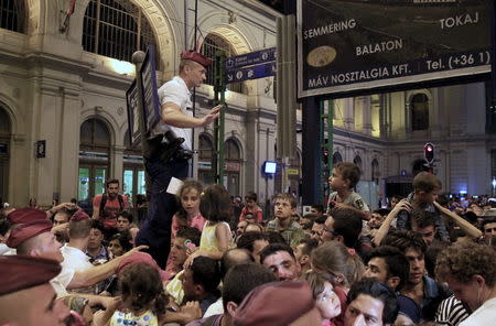 A policeman tries to control migrants as ticket control rules now mandate each passenger to have allocated seats on trains bound for the West from Budapest, Hungary, on August 31, 2015. REUTERS/Bernadett Szabo