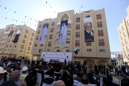 Posters depicting Palestinian President Mahmoud Abbas (R), Qatar's former Emir Sheikh Hamad bin Khalifa al-Thani (C) and Emir of Qatar Tamim bin Hamad al-Thani are seen on a building as people attend the opening ceremony of Qatari-funded construction project "Hamad City", in Khan Younis in the southern Gaza Strip January 16, 2016. REUTERS/Ibraheem Abu Mustafa