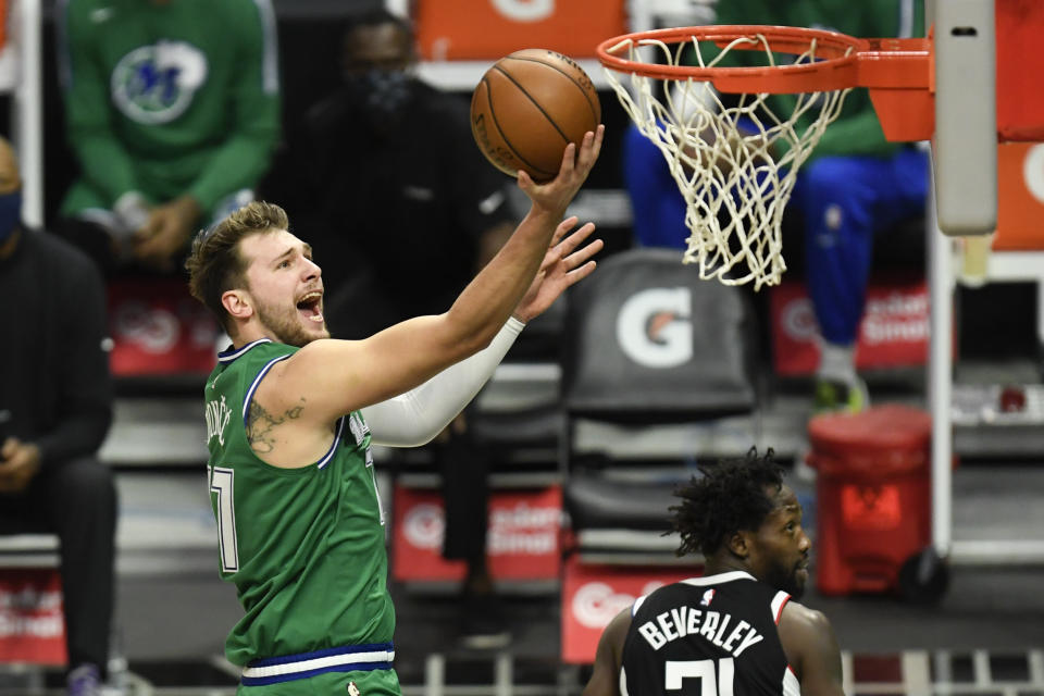 Dallas Mavericks guard Luka Doncic, left, goes up for a basket past Los Angeles Clippers guard Patrick Beverley during the first half of an NBA basketball game in Los Angeles, Sunday, Dec. 27, 2020. (AP Photo/Kyusung Gong)